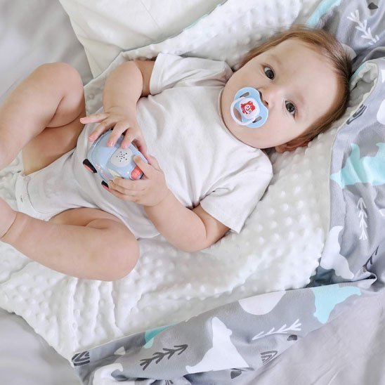 bébé étendu sur sa couverture bébé avec un jouet