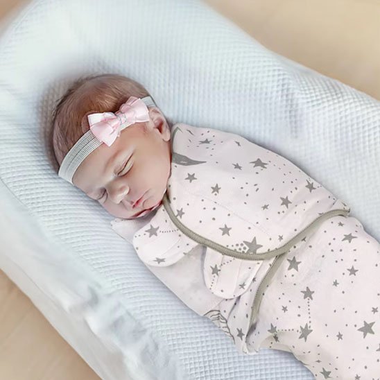 bébé dans une couverture emmaillotage blanche étoilé