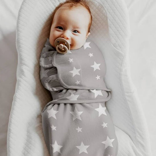 bébé dans une couverture emmaillotage grise étoilé